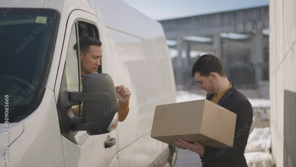 Delivery man giving a parcel to a businessman out of the drivers seat window Delivery man giving a parcel to a businessman out of the drivers seat window