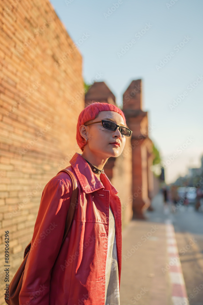Fototapeta premium Gen z girl leather fashion with punk Asian woman tourist of local city Southeast Asia travel trendy pink hairstyle young female punk traveler walking around in town