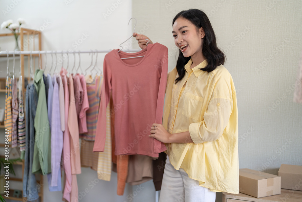 Young Asian girl Online consultation with stylist designer take online video course or training of stylish clothes on hangers clothing Asian Woman dressmaker working in fashion studio Young Asian girl Online consultation with stylist designer take online video course or training of stylish clothes on hangers clothing Asian Woman dressmaker working in fashion studio