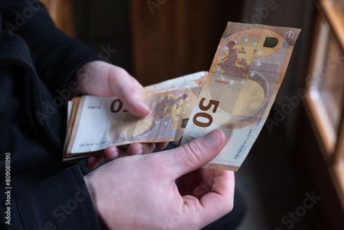 gros plan sur des mains qui tiennent une liasse de billets de 50 euros
