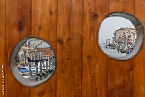 Chioggia cityscape in Venice Lagoon with narrow Vena water canal with colorful boats among old buildings 
