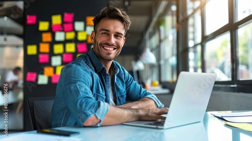 A smiling programmer is working on a laptop computer with many post-it notes in the background