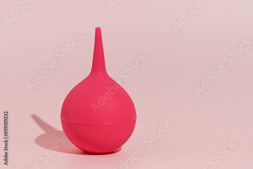 Image of a pink rubber enema on a pink isolated background. Concept of medicine and pharmaceutical products, body detox. Place for your text and design