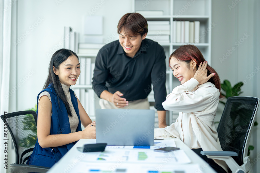 Three people are sitting at a table with a laptop in front of them. They are smiling and seem to be having a good time Three people are sitting at a table with a laptop in front of them. They are smiling and seem to be having a good time