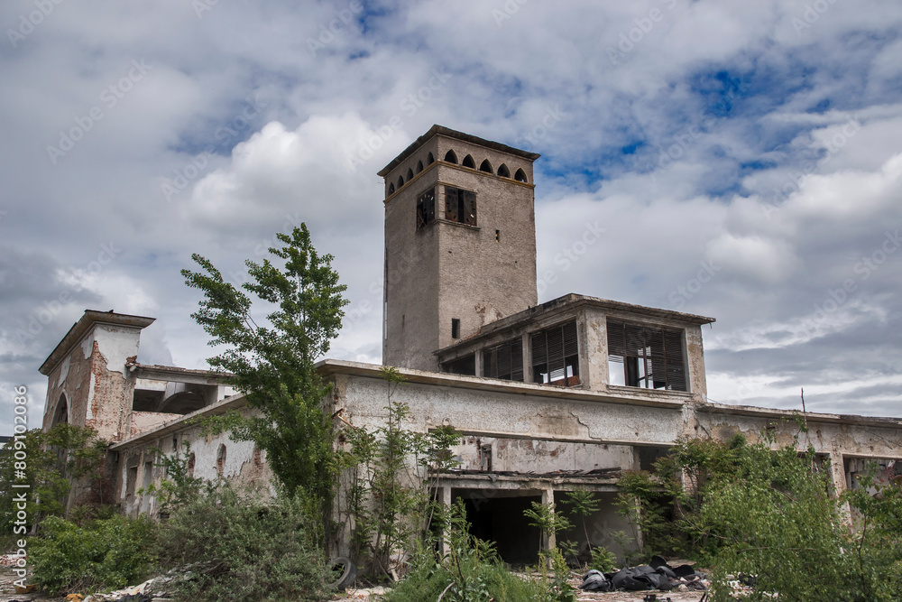 Fototapeta premium Abandoned crumbling vintage obsolete industrial building closeup in sunny day