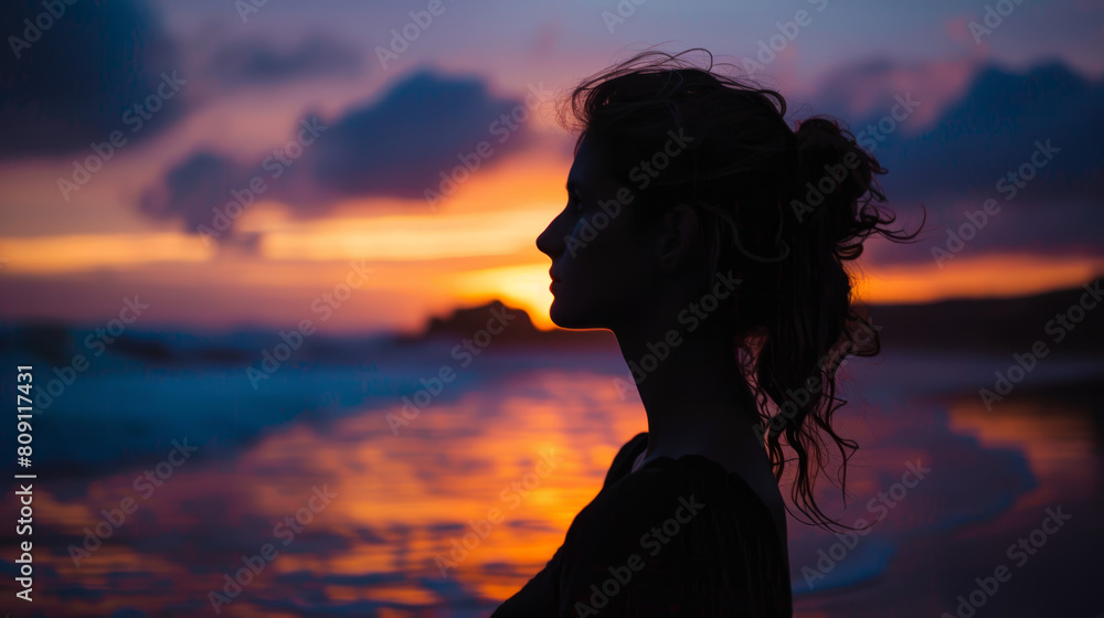 A woman is standing on the beach, looking out at the ocean