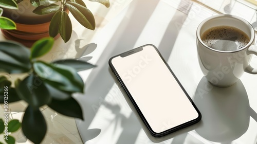 Smartphone with blank screen and coffee cup on white table. Mock up