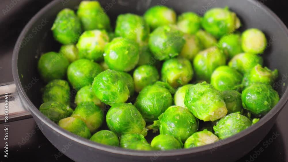 Green brussels sprouts sizzles and simmers on a stove. Selective focus Green brussels sprouts sizzles and simmers on a stove. Selective focus