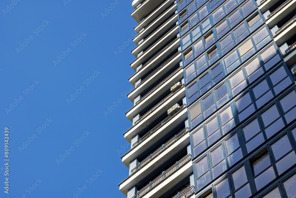 Skyscraper towering above urban design, framed by clear blue sky Skyscraper towering above urban design, framed by clear blue sky