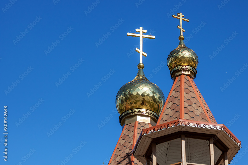 A church building with two gold crosses on top of its steeple against the sky