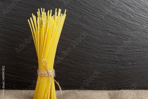 raw spaghetti pasta from durum wheat vertically on a dark background