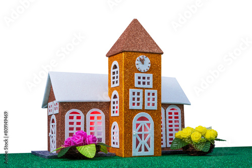 On a white background, a small brown toy chapel with light in the windows