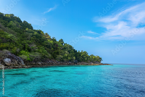 Real tropical green island photo and shallow turquoise sea water color with coral reef underwater in national park travel destination with cloud blue sky background