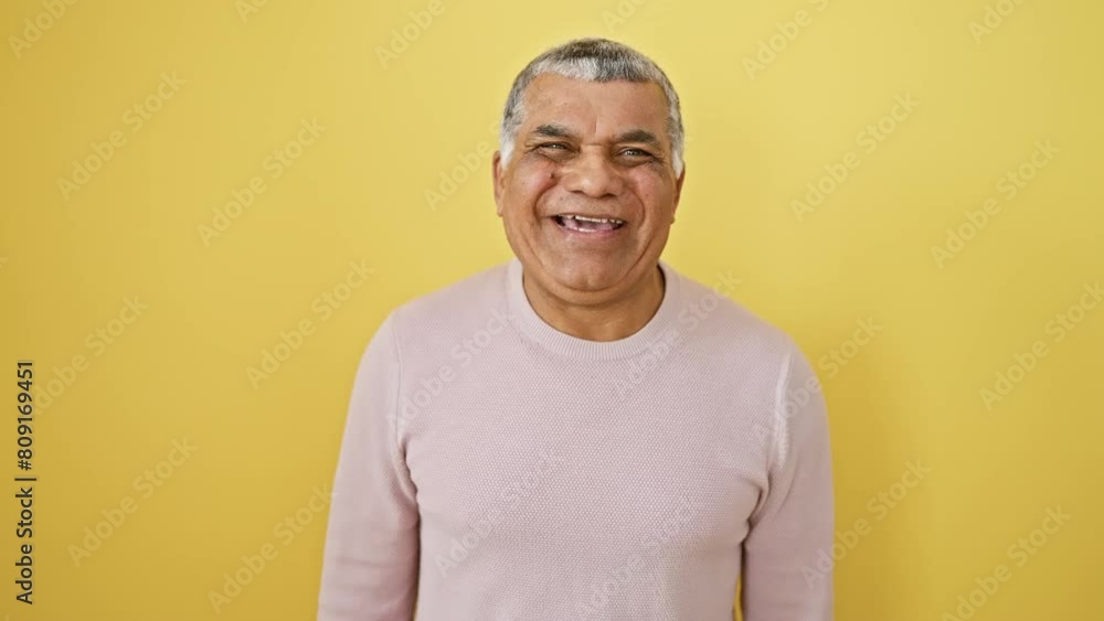 Grey-haired latin man in a sweater hilariously making a fish face, pulling off a crazy yet comical expression with his eyes and mouth against a vibrant yellow background. Grey-haired latin man in a sweater hilariously making a fish face, pulling off a crazy yet comical expression with his eyes and mouth against a vibrant yellow background.