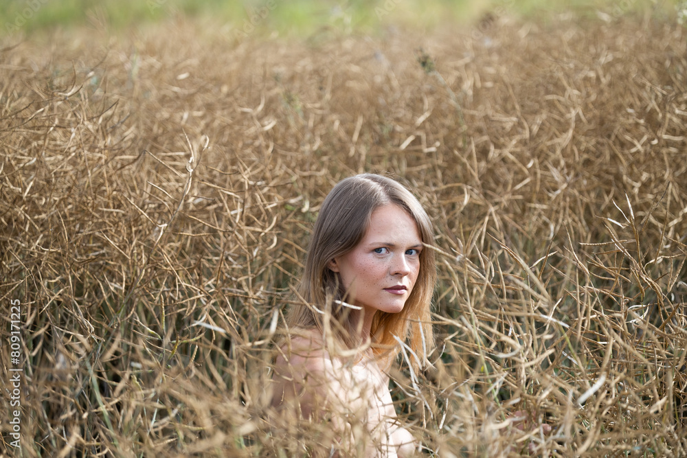 Portrait of a beautiful young woman with freckles on her face, autumn ripe canola in the background Portrait of a beautiful young woman with freckles on her face, autumn ripe canola in the background