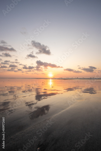 Fantastic sunset on the dream beach of Kuta  small waves setting over the sea and the reflection of the sky in the shallow water. News Bali in Indonesia