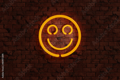 Yellow neon lights sign of smiley face on a red brick wall. Illustration of the concept of happiness, fun, joy and positive feeling