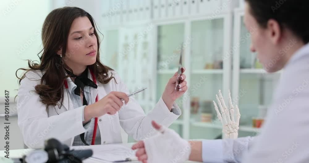 Focused woman doctor examines X-ray image of patient hand Focused woman doctor examines X-ray image of patient hand