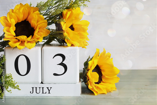 National Plastic Bag Free Day. White wood calendar blocks with the date July 3rd and beautiful sunflower bouquet with bokeh. Selective focus with blurred background. 