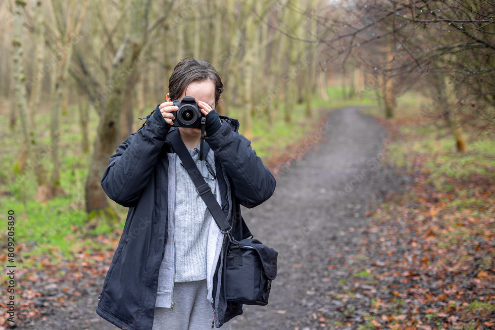 Young photographer teenage girl using DSLR camera outdoors in wood taking photo Young photographer teenage girl using DSLR camera outdoors in wood taking photo