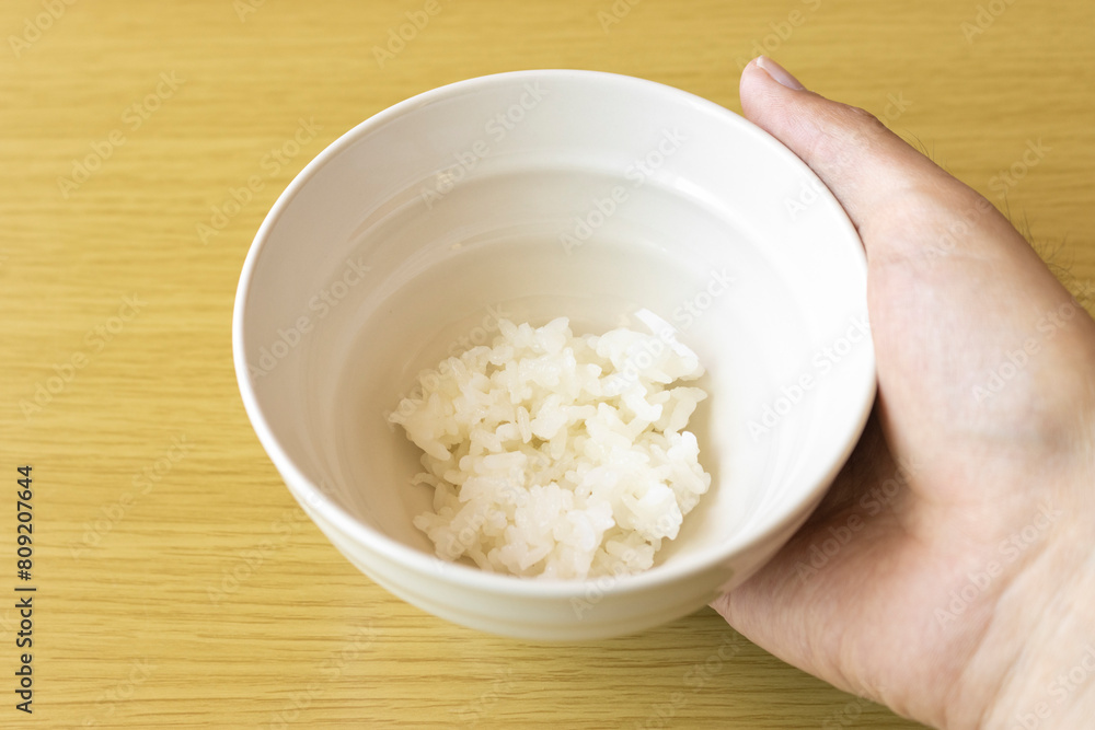 茶碗に入れた少しのご飯を持つ男性の手。貧困のイメージ 茶碗に入れた少しのご飯を持つ男性の手。貧困のイメージ