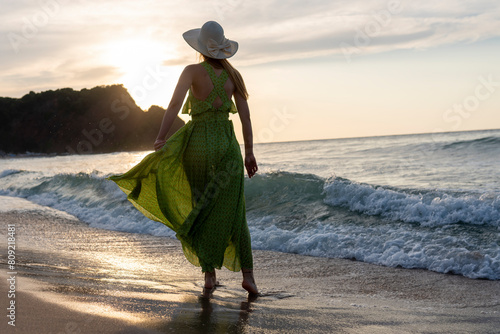 Happy woman walking on beach at sunset.Beautiful female happy relax walking on beach near sea when sunset in evening.