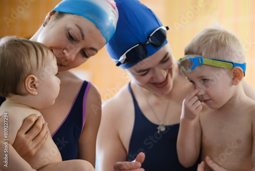Kids communicating n indoor swimming pool with teacher. Happy time together and general physical activity for kids, early development. Boy kids early development 