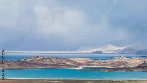 Tajikistan, Gorno-Badakhshan Autonomous Region (GBAO), Pamir Highway, panoramic view of sunny Karakul lake with grey clouds and storm over snowy mountains