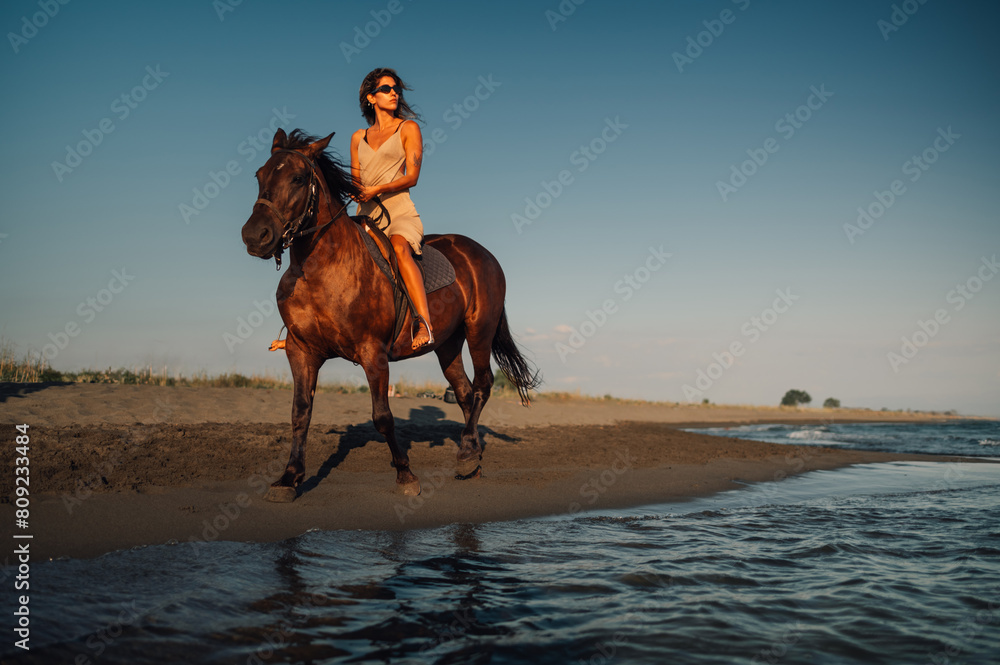 Shot from a sea of a young woman on horseback alongside the summer beach Shot from a sea of a young woman on horseback alongside the summer beach