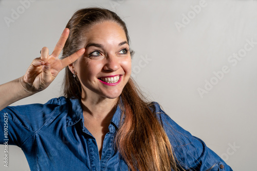 Mujer haciendo un numero dos con sus dedos. Mujer sonriente y feliz haciendo la V de victoria con su mano