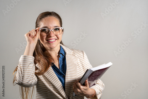 Mujer universitaria sosteniendo sus notas y libros mientras sonrie a cámara photo