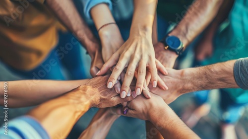 A group of individuals standing in a circle, stacking their hands together in a show of unity and teamwork.