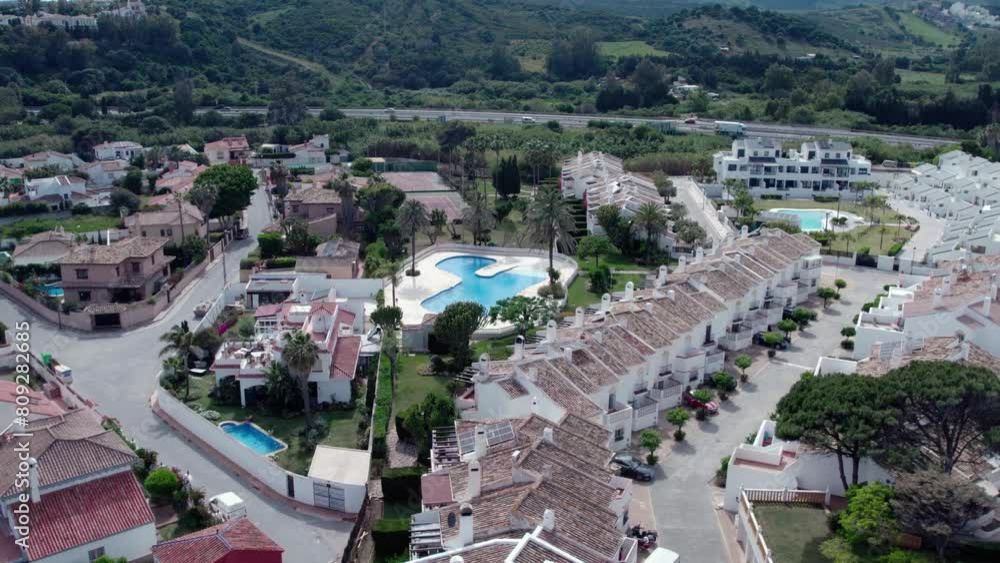 Aerial flyover of architecturally-designed modern prestige homes with pools in outer suburban Estepona, Spain