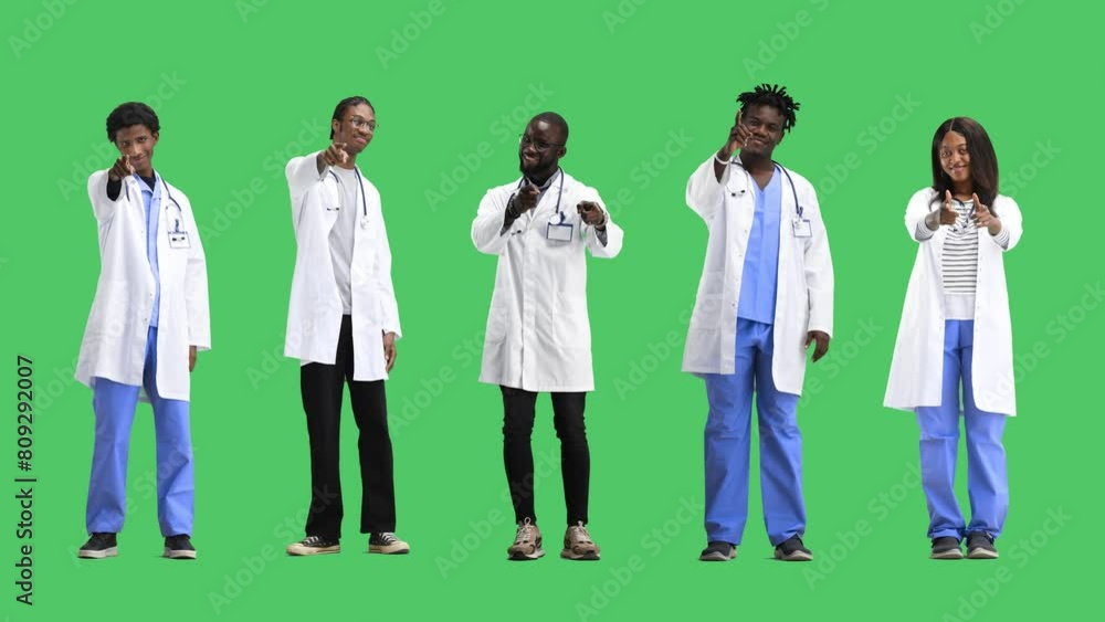 A group of doctors, in full height, on a green background, points forward A group of doctors, in full height, on a green background, points forward