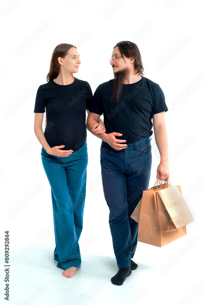 Portrait happy young pregnant woman and her husband with shopping bags and touching her big belly isolated on white background. Pregnancy shopping concept happy young family with shopping bags