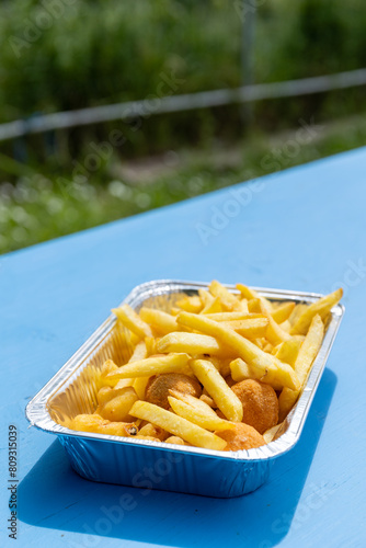 Aluminium tray filled with deep fried food in a street food kiosk: french fries, Olive all'Ascolana, typical Italian meat filled olives, and mozzarella fried balls. Unhealthy fried food.