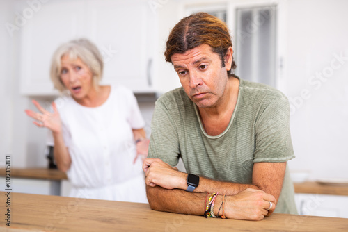 Upset middle aged man dont speaking after discord with aged wife behind
