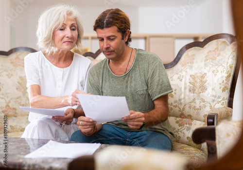 Helpful man helping elderly woman to sign financial documents