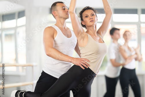 Young man and adult woman perform paired ballet dance in studio