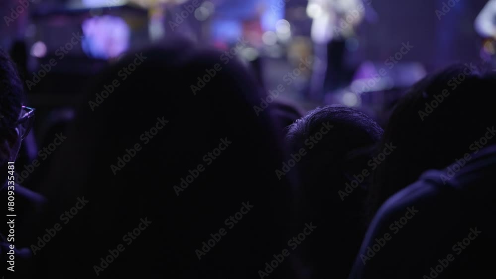 An unrecognizable woman enjoys a live concert, dancing in the middle of the crowd.
An unrecognizable woman enjoys a live concert, dancing in the middle of the crowd.
