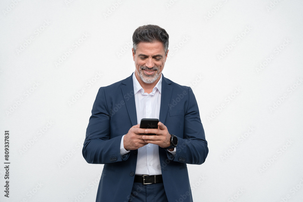 Smiling Latin business man using smartphone mobile phone screen device, scrolling app, working for communication with partners. Mature businessman in suit holding cellphone isolated, white background Smiling Latin business man using smartphone mobile phone screen device, scrolling app, working for communication with partners. Mature businessman in suit holding cellphone isolated, white background
