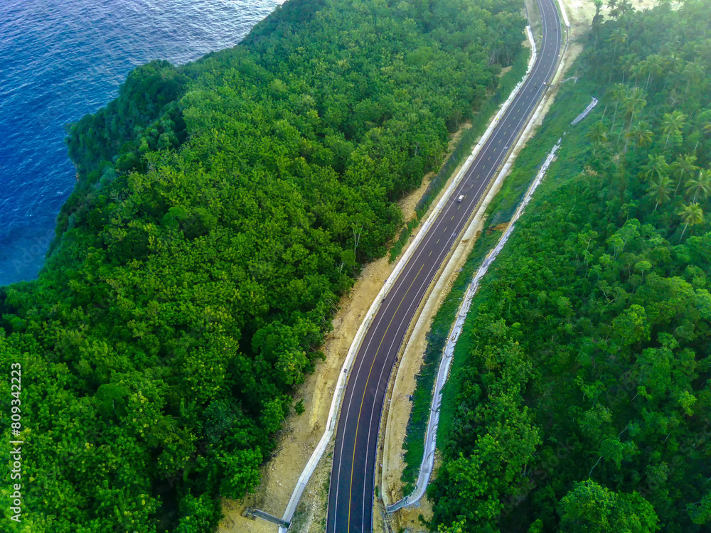 a curvy coastal road snaking along a bright blue ocean.