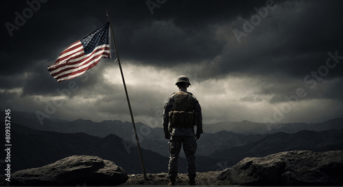 A man stands on a mountain with a flag near him photo