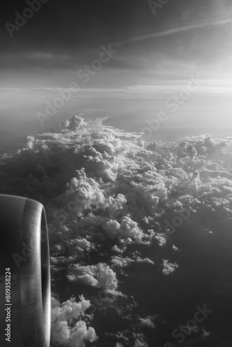 View from the window of an airplane flying above clouds, black and white photo.