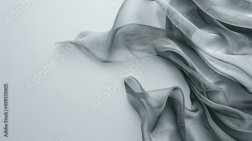 Sheer grey fabric with delicate waves on white surface photo