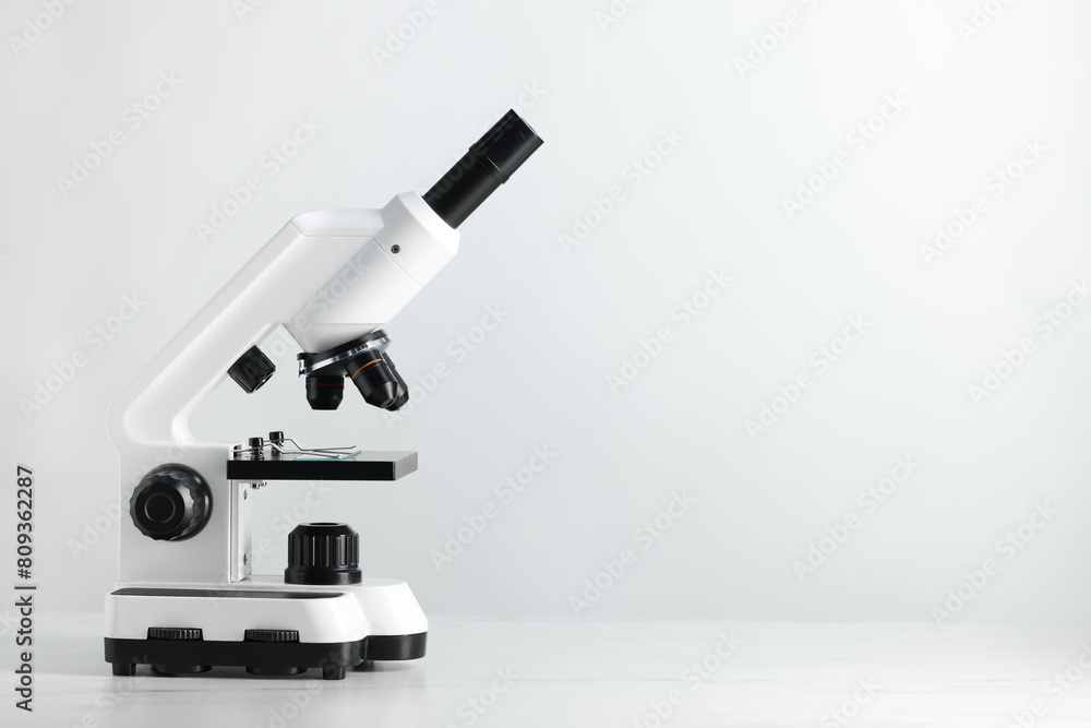 Modern microscope on white table, space for text Modern microscope on white table, space for text