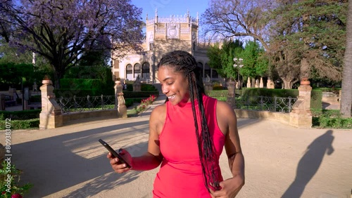 Mujer muy alegre sonriendo contenta con su teléfono móvil mientras que pasea por una ciudad europea un día soleado con cielo azul al atardecer. photo