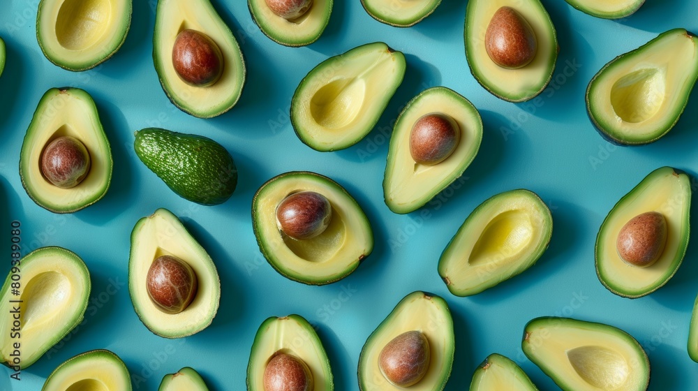 Avocado slices and whole avocados arranged in a whimsical pattern, captured from above against a cyan backdrop, isolated
