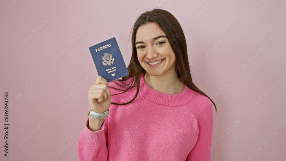 Confident young hispanic woman flaunts us passport, showcasing a hearty, happy smile with healthy teeth, exuding positive attitude over pink isolated background Confident young hispanic woman flaunts us passport, showcasing a hearty, happy smile with healthy teeth, exuding positive attitude over pink isolated background
