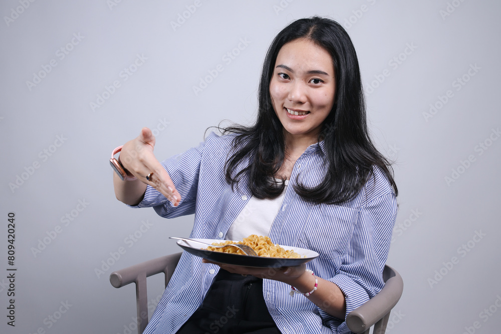 Potrait Of Cheerful Female College Student While Holding And Pointing Noodles Potrait Of Cheerful Female College Student While Holding And Pointing Noodles